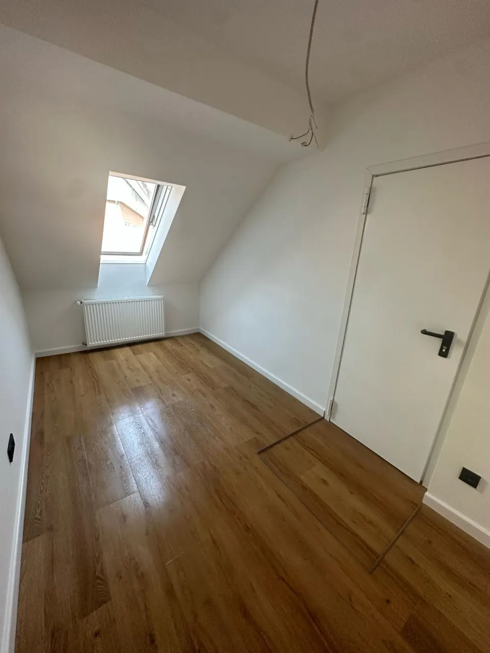 Echtes Referenzfoto eines renovierten Dachgeschosszimmers mit Laminatboden und Dachfenster