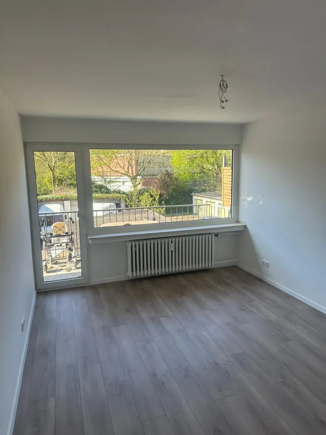 Echtes Referenzfoto eines renovierten Wohnraums mit Fenster und Laminatboden