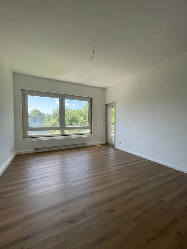 Referenzfoto im Album Alle: Echtes Referenzfoto eines renovierten Wohnraums mit Laminatboden und großer Fensterfront