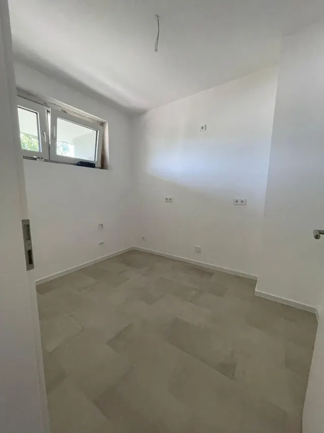 Echtes Referenzfoto eines fertig renovierten Zimmers mit grauem Bodenbelag
