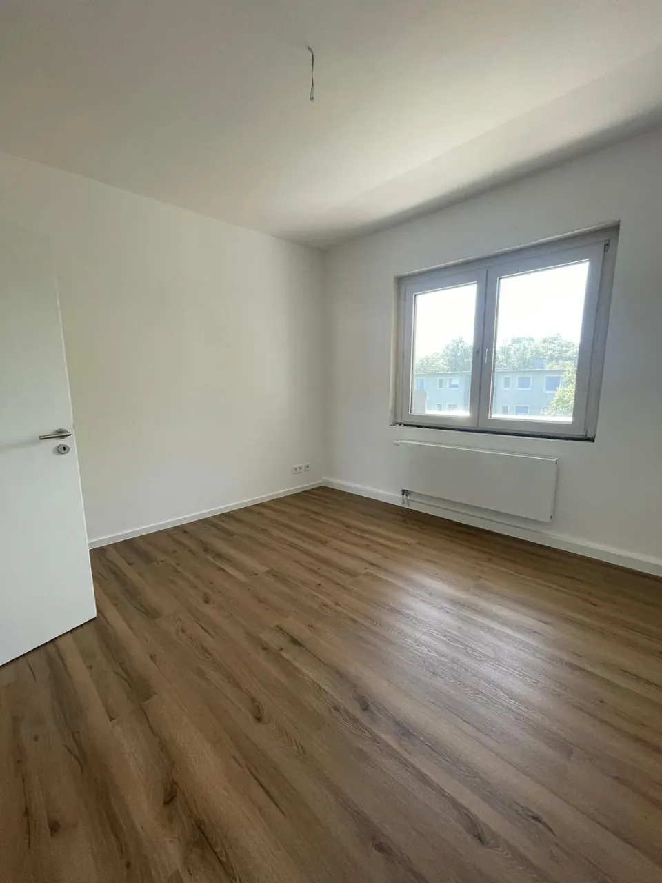 Echtes Referenzfoto eines hellen renovierten Zimmers mit Laminatboden