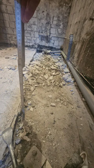Geöffneter Bodenbereich im Badezimmer mit freigelegtem Untergrund und Anschlusszone