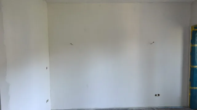 Breite Wohnraumwand mit hellem Anstrich und noch sichtbaren Bearbeitungsspuren